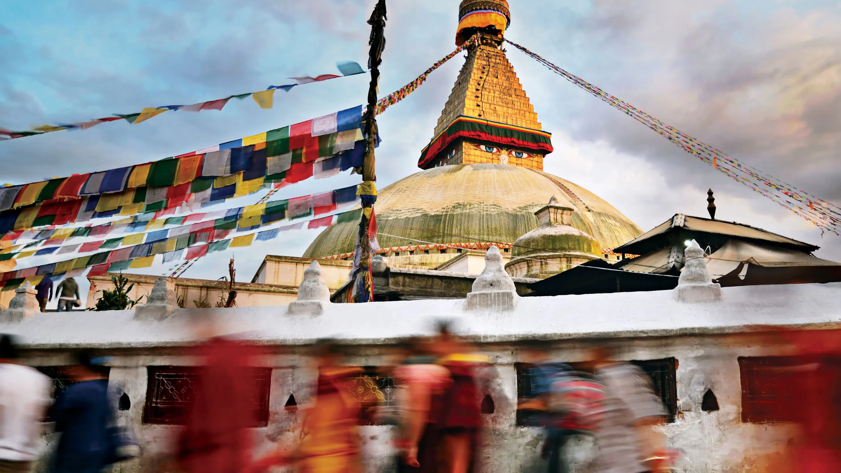 A group of people walking past a pagoda in kathmandu.