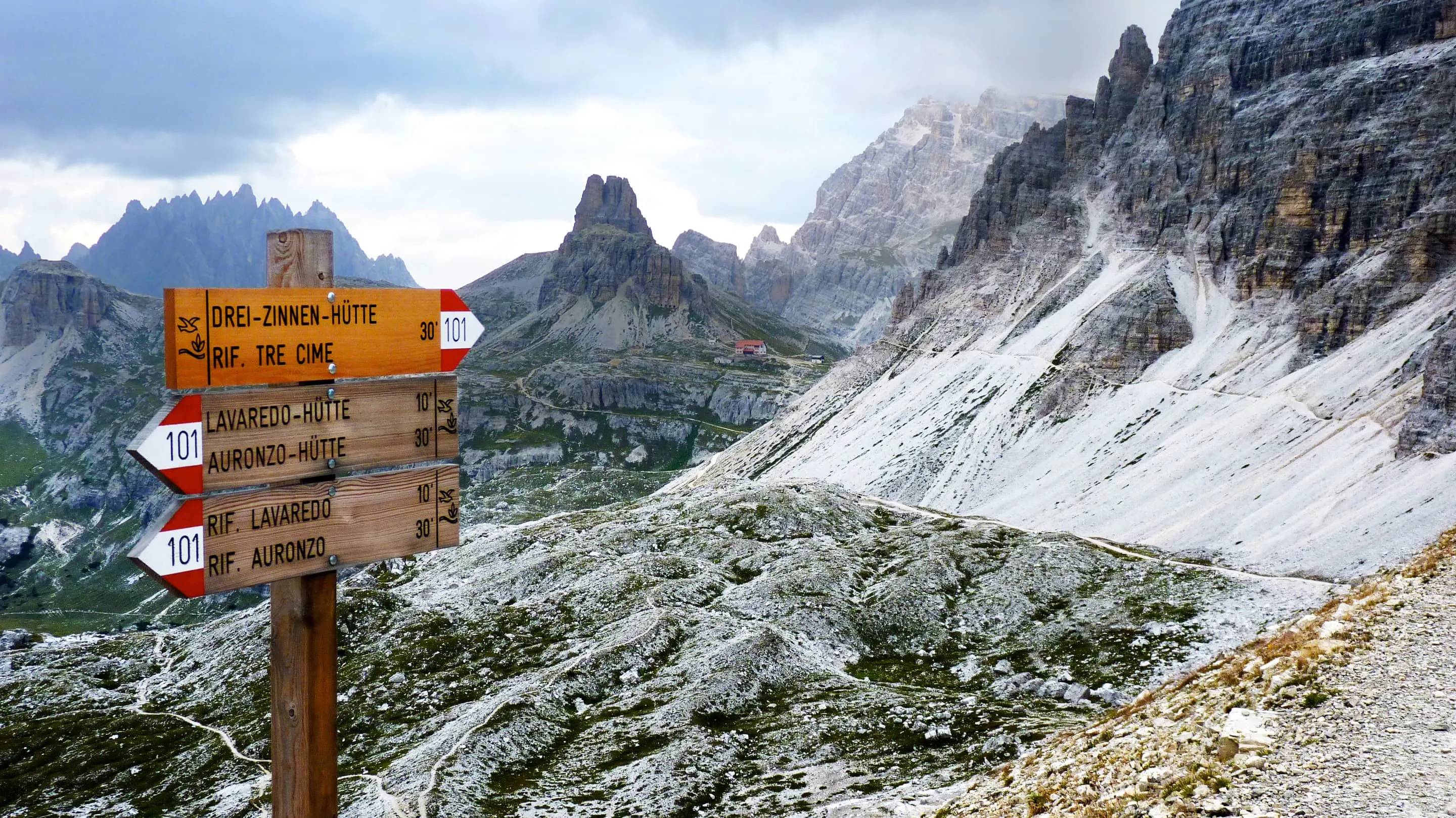 A wooden sign on the side of a mountain trail.