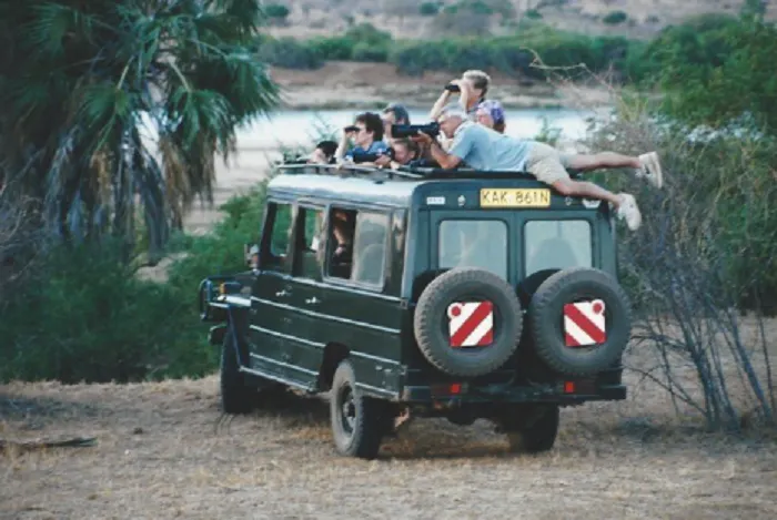 A group of people sitting on the top of a jeep.