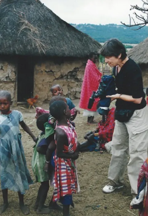 A woman with a camera in front of a group of children.