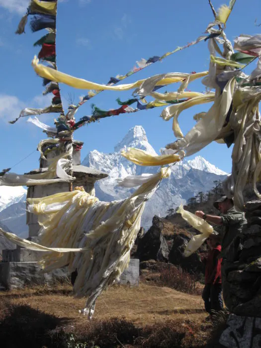 A group of people standing in front of a temple with a mountain in the background.