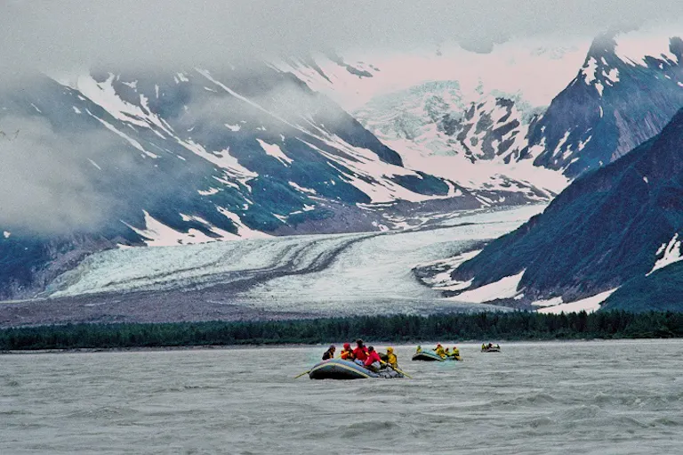 A group of people on a boat in front of a glacier at Yukon & Alsek River in Alaska