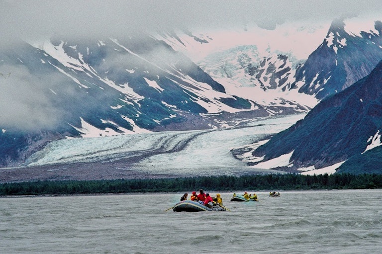 A group of people on a boat in front of a glacier at Yukon & Alsek River in Alaska