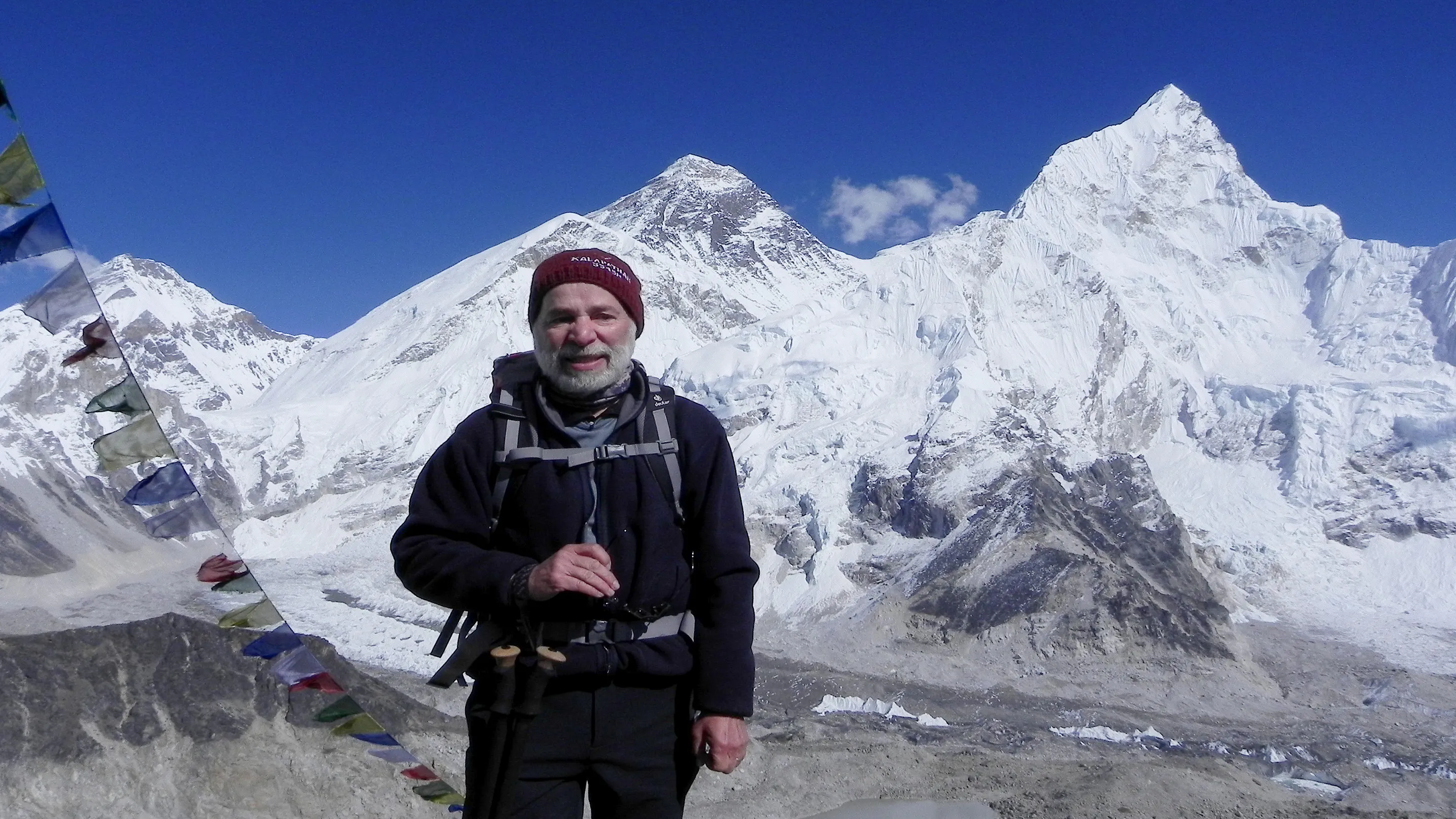 A man standing in front of a mountain with flags.