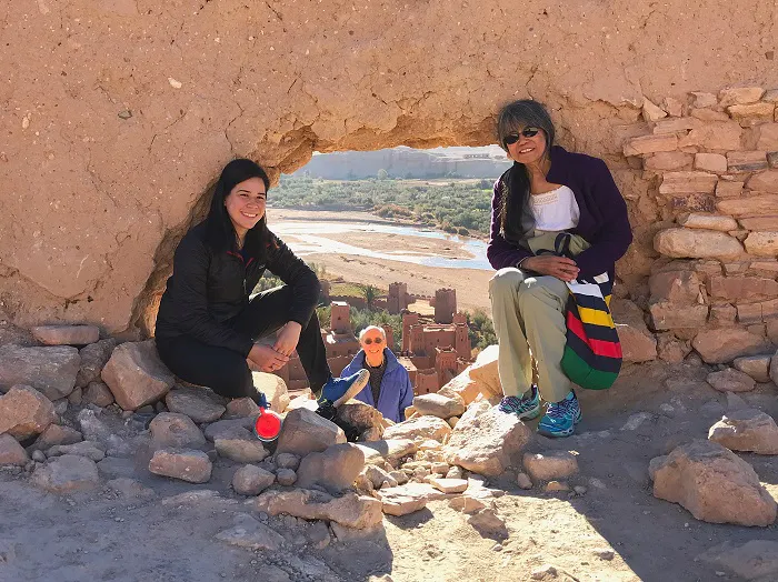 Three women sitting in a hole in a rock wall.