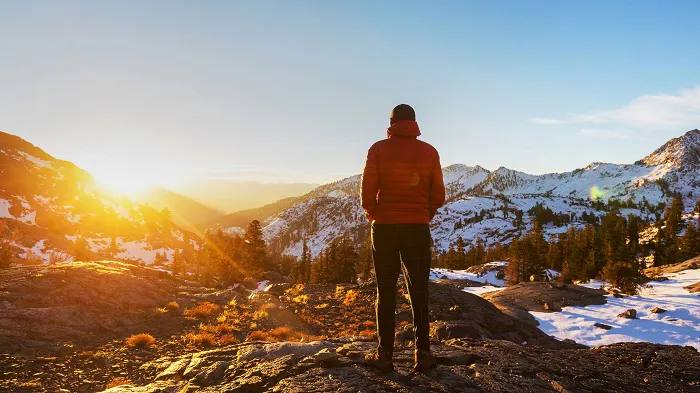A man standing on top of a mountain at sunset.