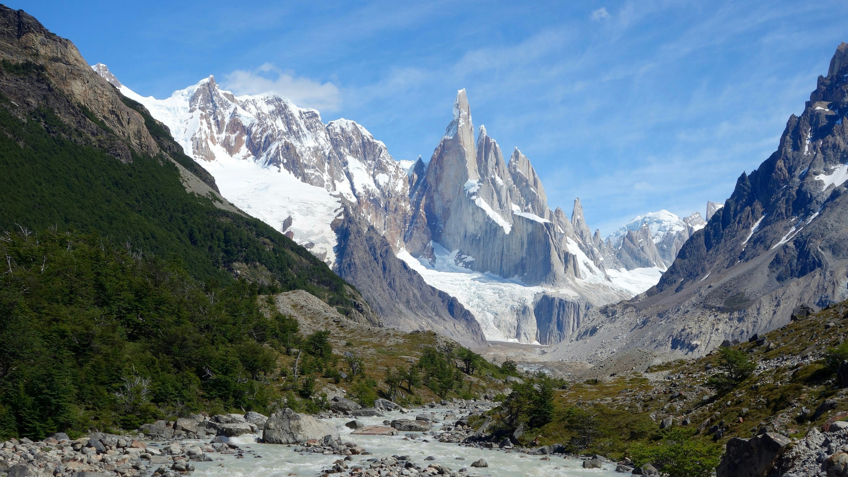 A river runs through the mountains near a glacier.