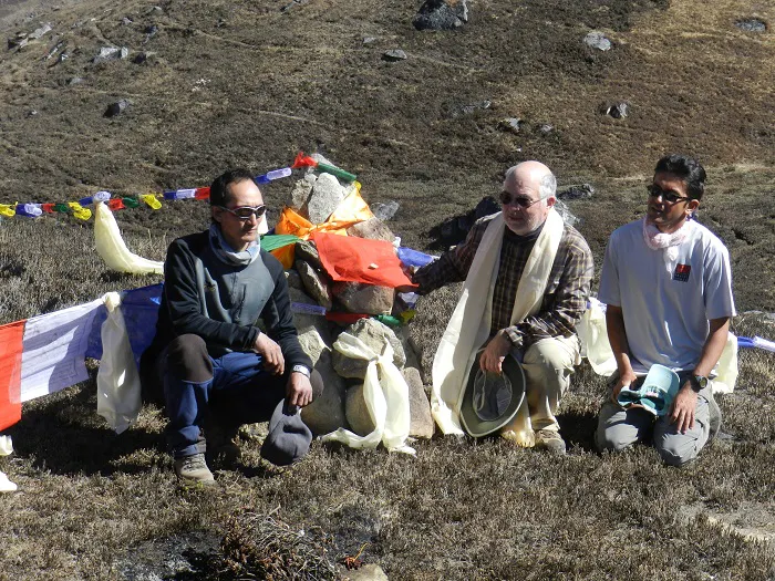 Three men posing for a photo on a hillside.