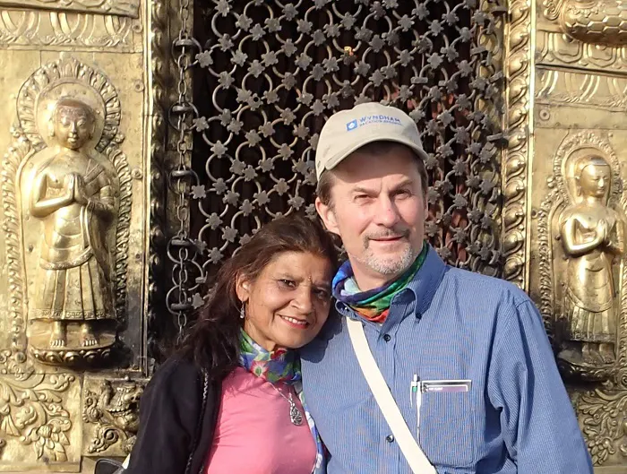 A man and woman posing for a photo in front of a golden gate.