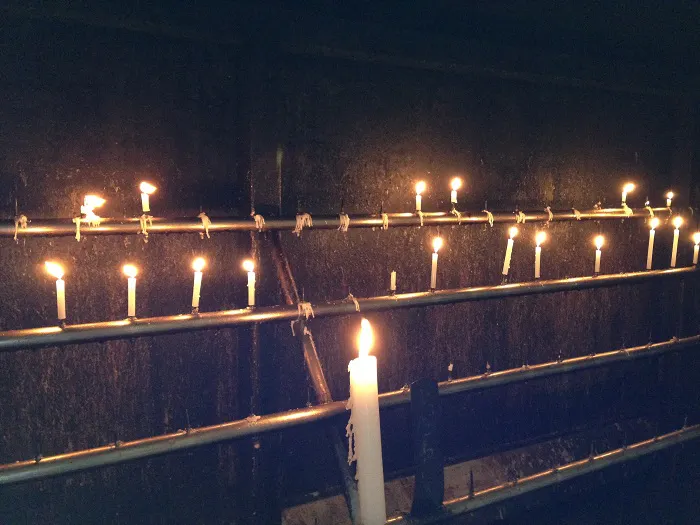A row of lit candles in a dark room.