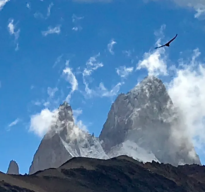 A bird flies over a mountain in the sky.