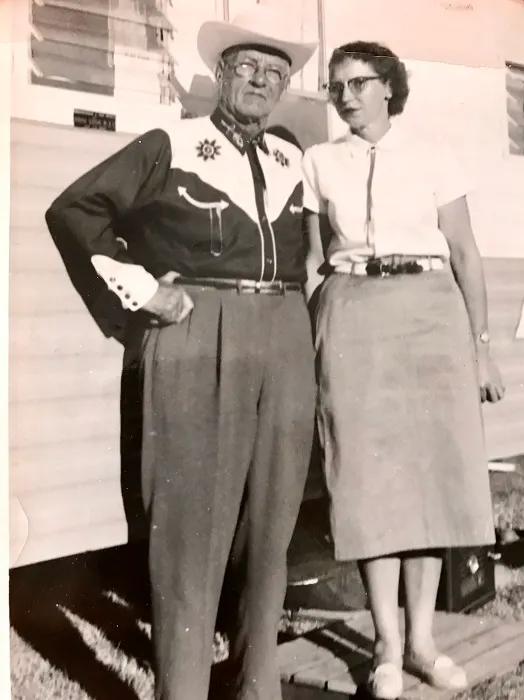 An old photo of a man and woman standing in front of a trailer.