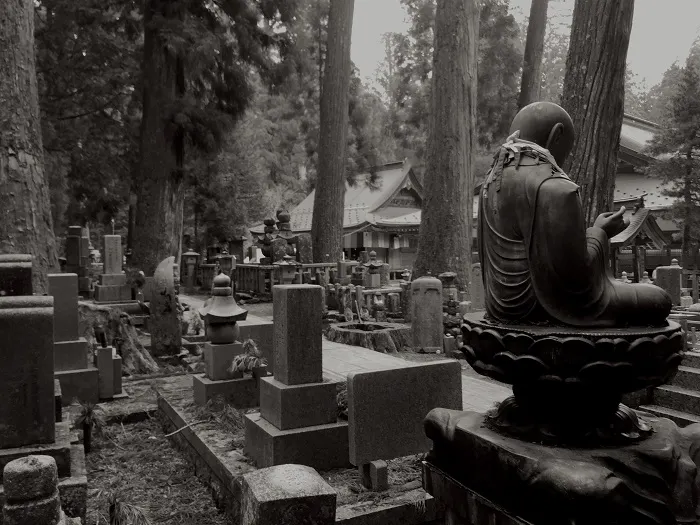 A black and white photo of a cemetery with buddha statues.