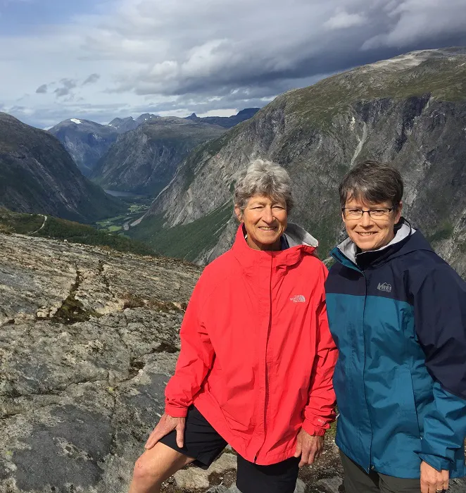 Two women standing on top of a rocky mountain.