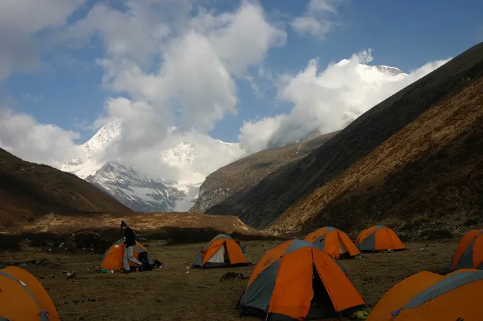 A group of tents set up in a field with mountains in the background.