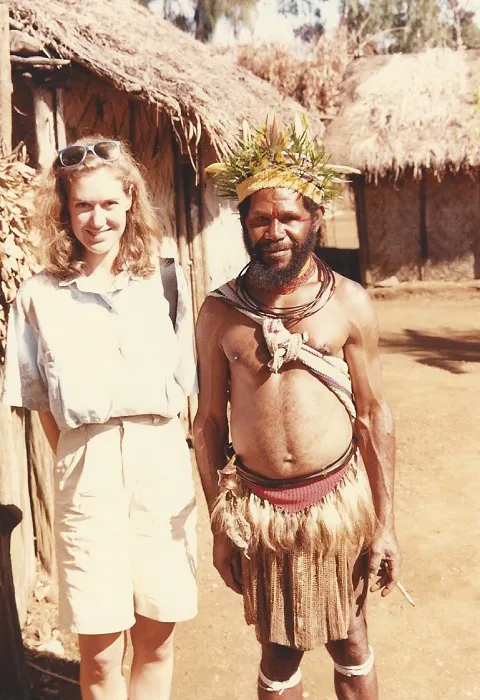 A woman and a man standing in front of a hut.