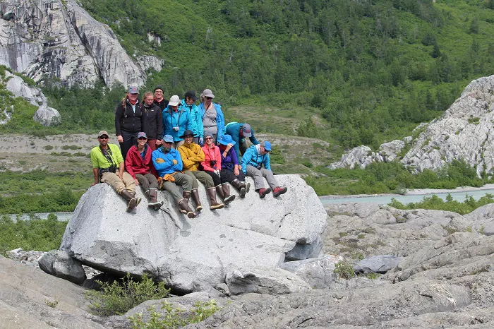 A group of people posing on rocks near a river.
