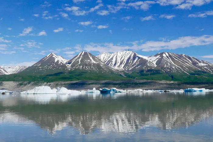 A lake with icebergs and mountains in the background.