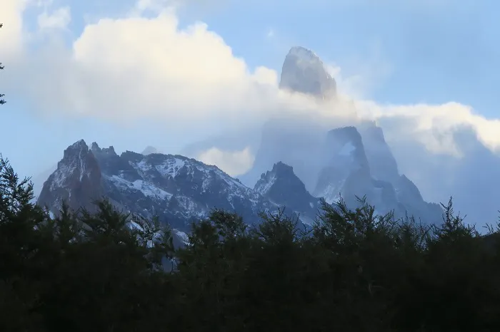 A mountain covered in snow with trees in the background.