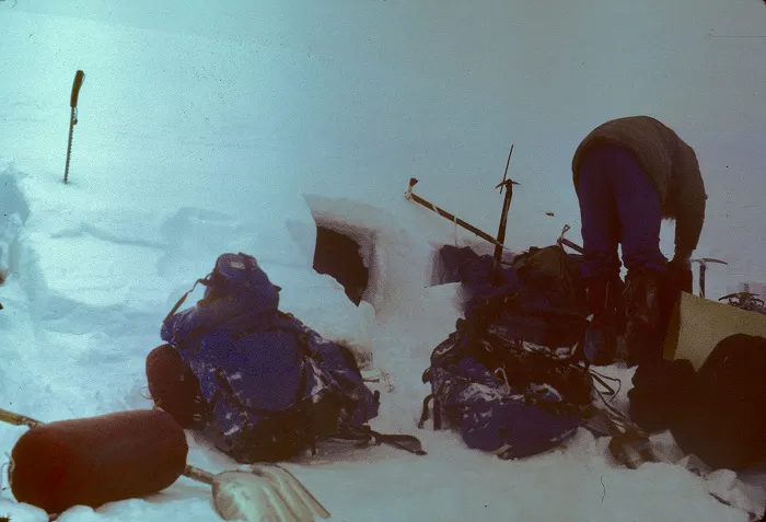 A man is standing in the snow with a backpack.