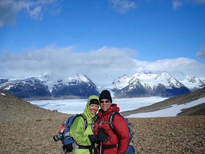 Two people posing in front of a mountain with mountains in the background.