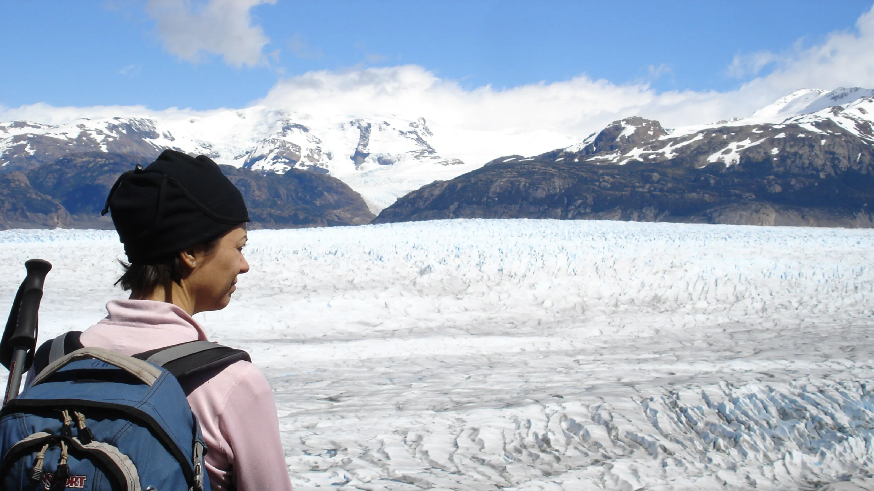 A woman is standing in front of a glacier.
