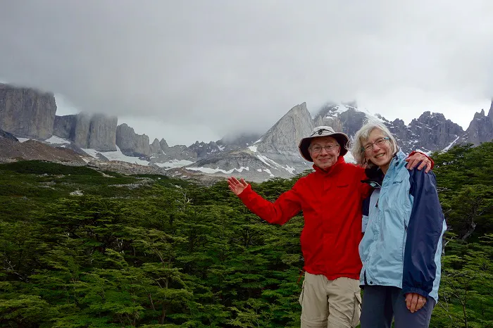 Two people posing for a picture in front of mountains.