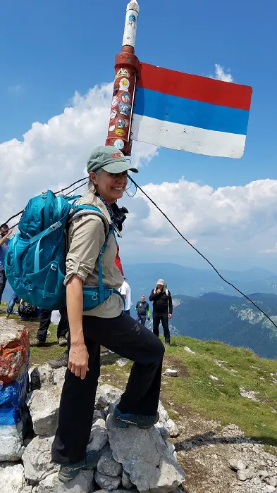 A woman with a backpack standing on top of a mountain