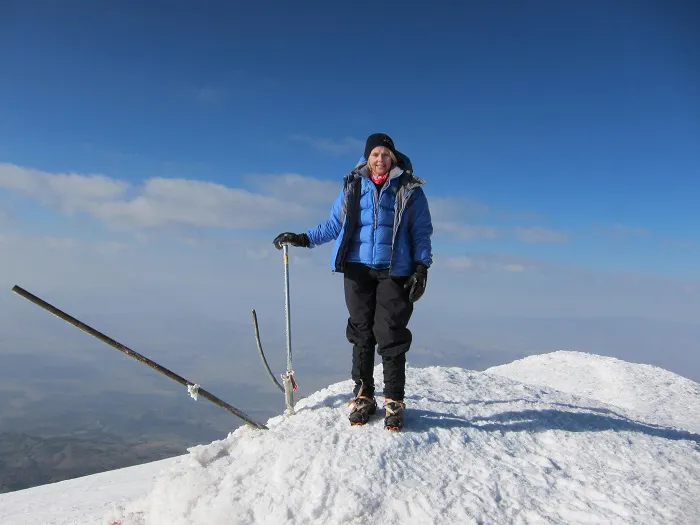 A woman standing on top of a snow covered mountain.
