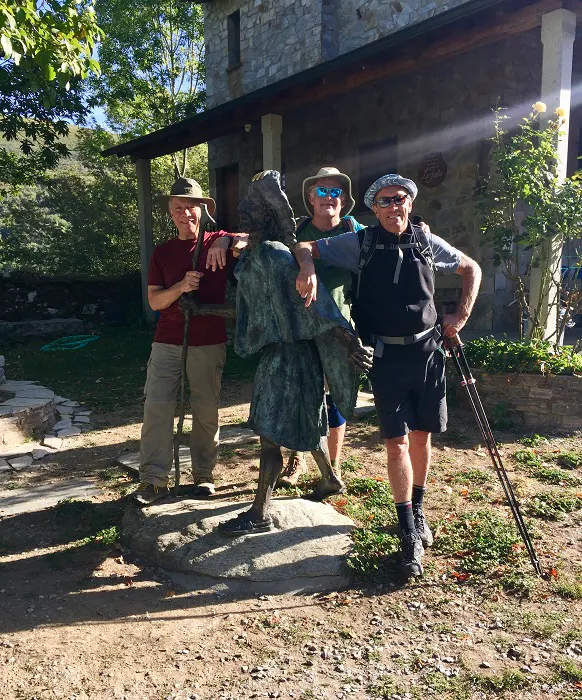Three men standing next to a statue.