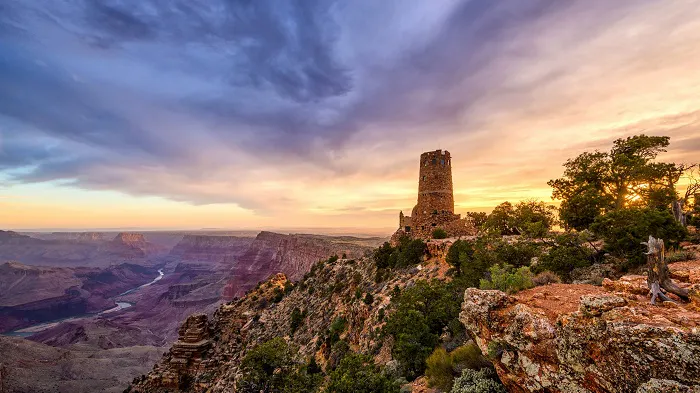 The grand canyon at sunset with a tower in the background.