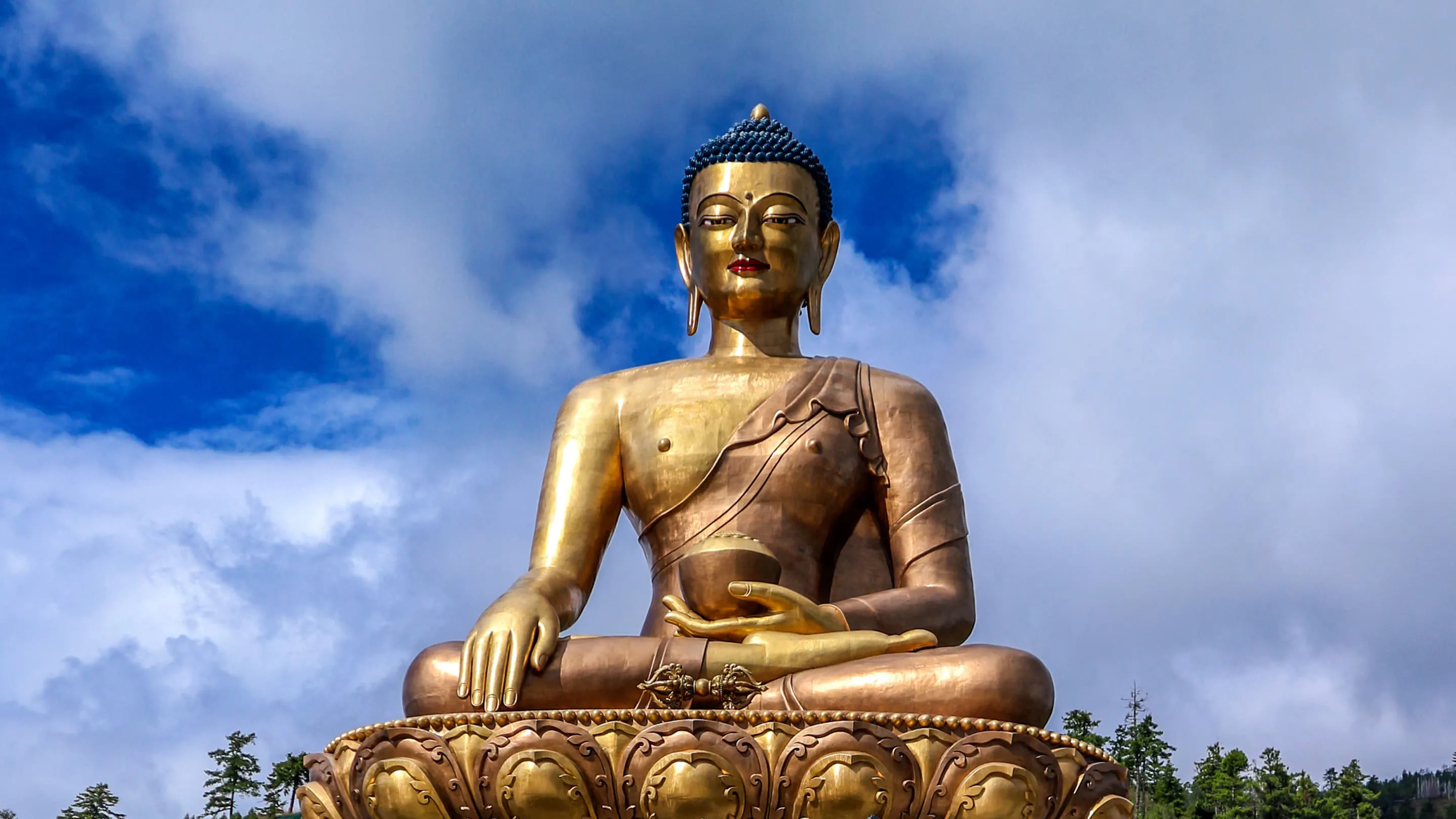 A golden buddha statue sits on top of a mountain.