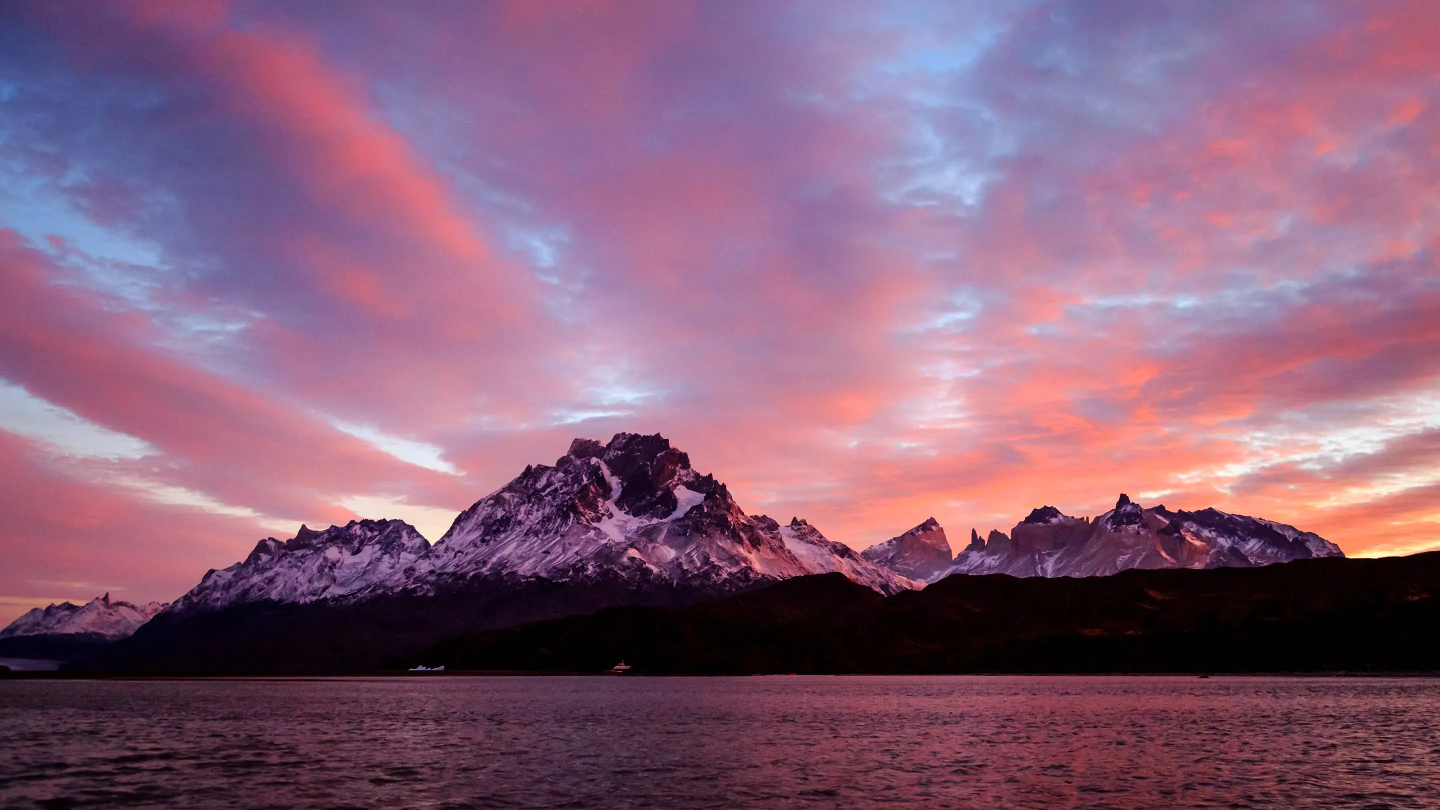 A sunset over a lake with mountains in the background.