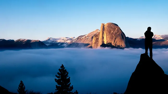 A silhouette of a man standing on top of a mountain.