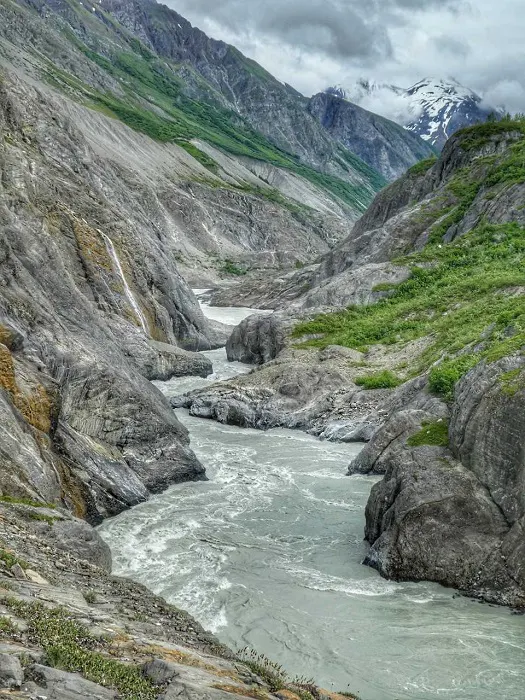 A river runs through a rocky area with mountains in the background.