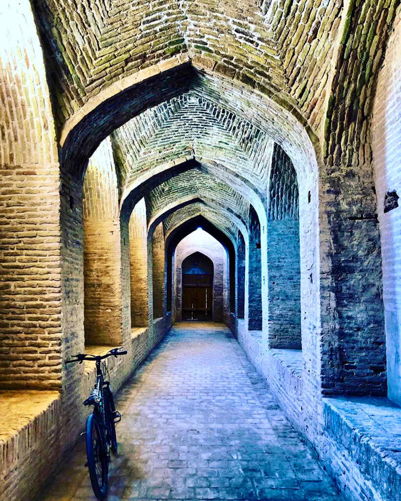 A bicycle is parked in an archway in an old building.
