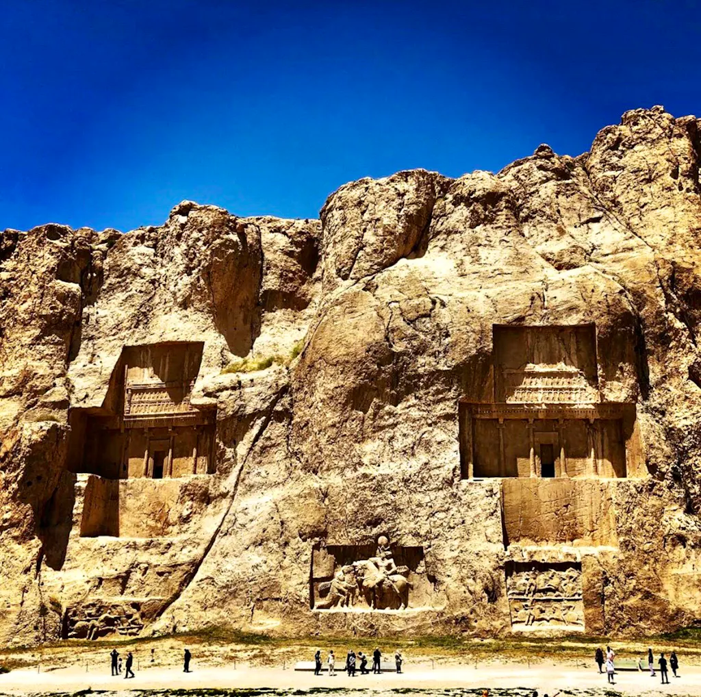 A group of people standing in front of a large rock formation.