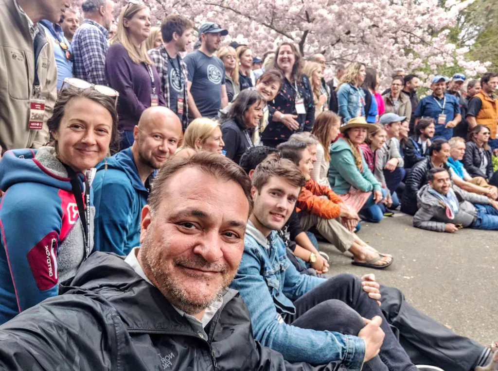 A group of people posing for a photo in front of cherry blossoms.