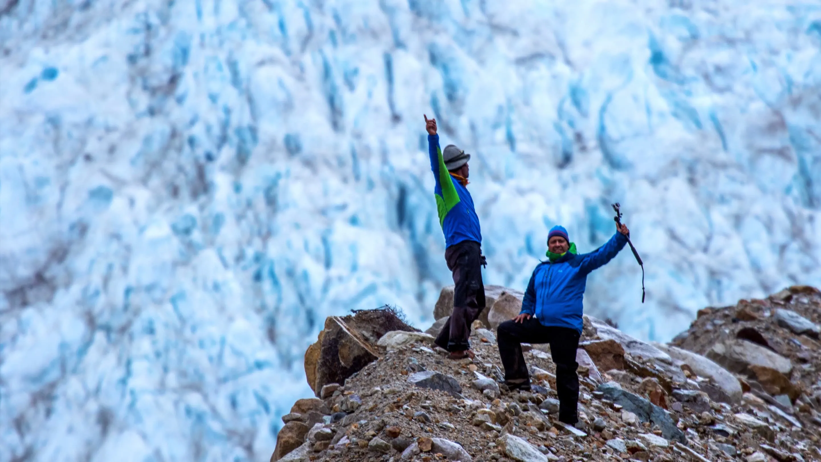 Two people standing on top of a glacier.