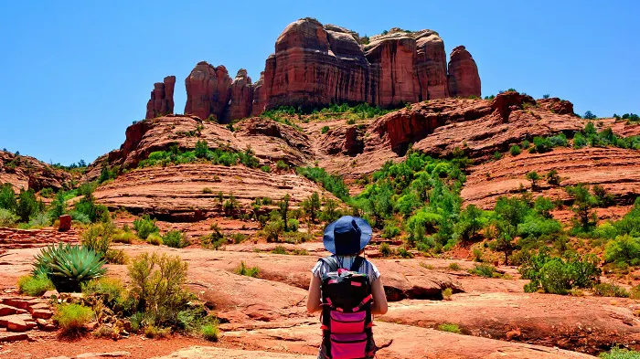 A girl with a backpack looking at red rocks in sedona, arizona.