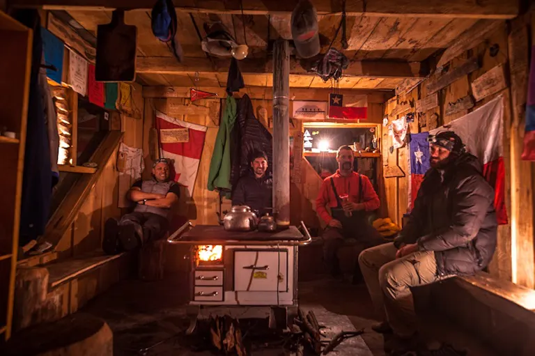 the inside of a wooden mountain lodge; a group of people resting after a long hike 