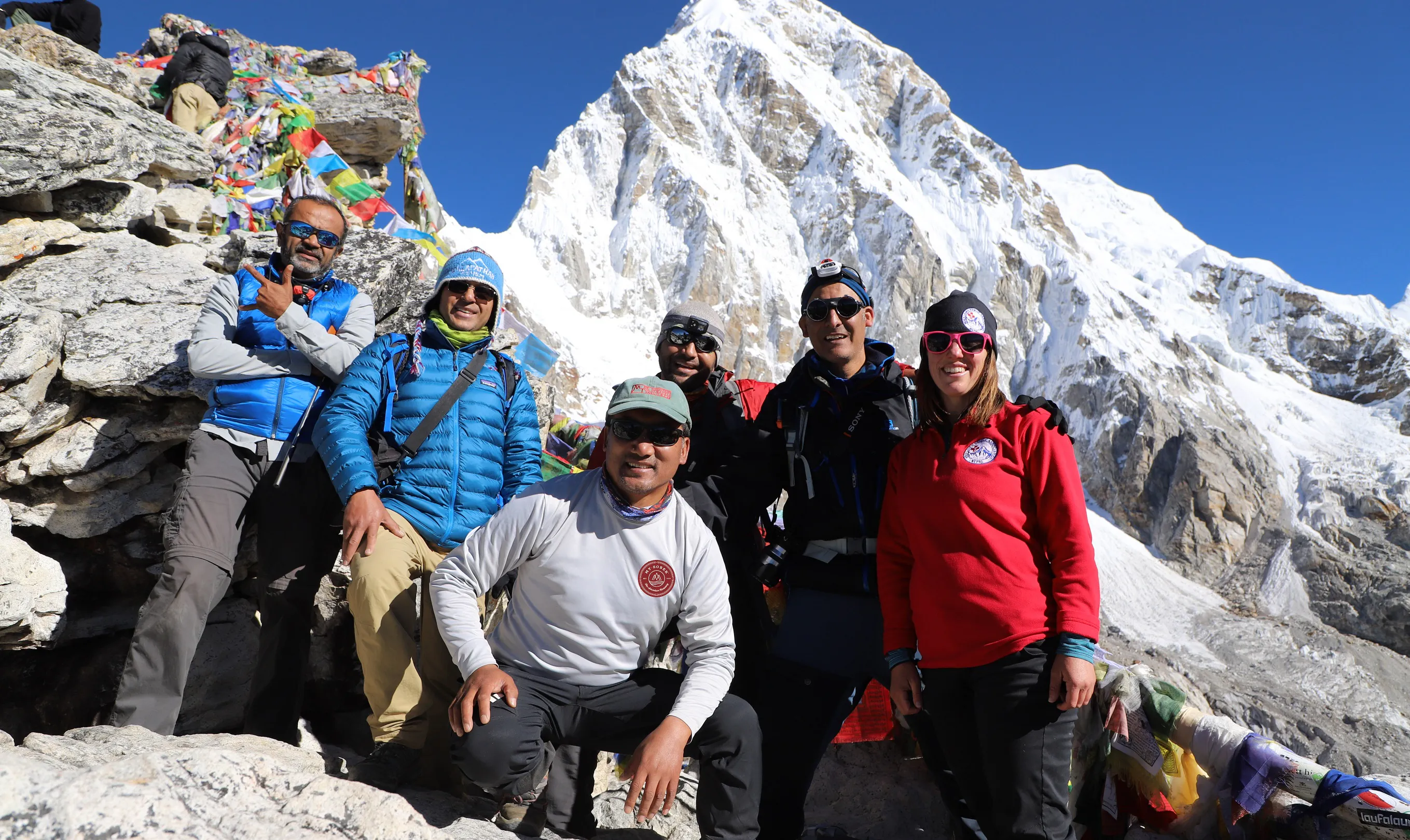 A group of people posing in front of a mountain.