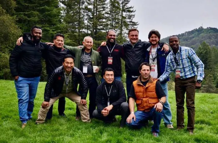 A group of men posing for a photo in a grassy field.