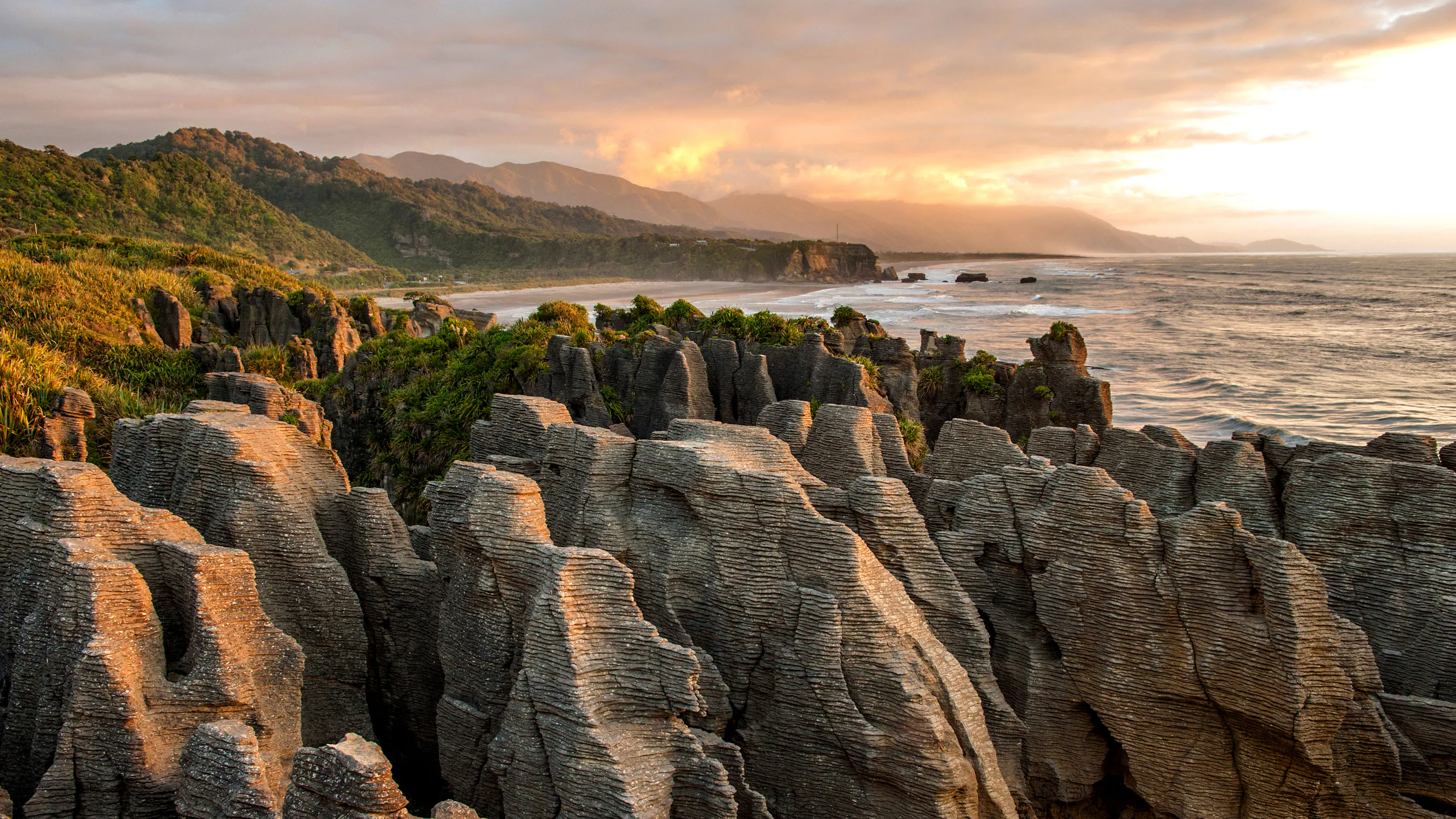 The rock formations at sunset on a beach in new zealand.