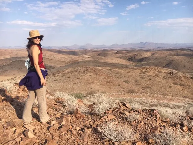 A woman standing on top of a hill in the desert.