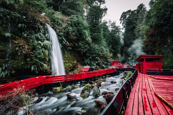 A red boat with a waterfall in the background.