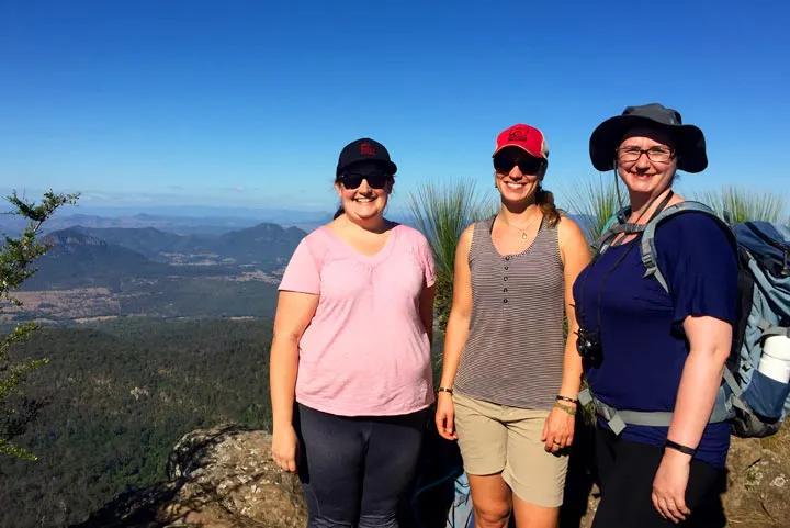 Three women solo travel to the top of a mountain.
