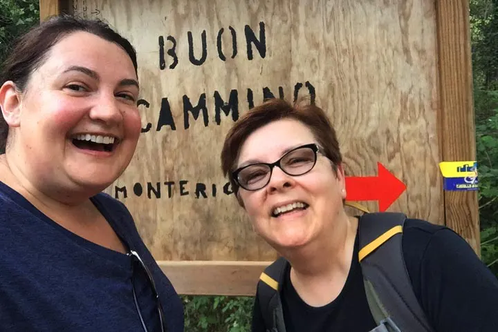 Two women standing next to a sign while on solo travel.