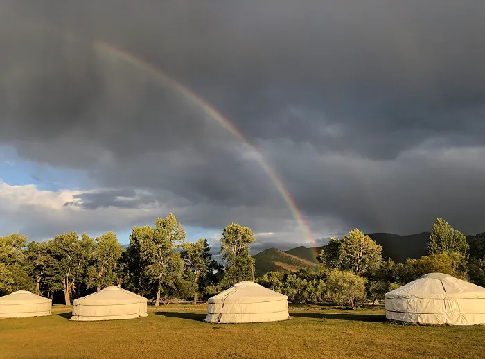 Two yurts with a rainbow in the sky.