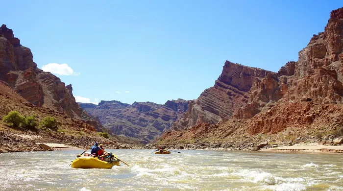 A group of people rafting down a river in the grand canyon.